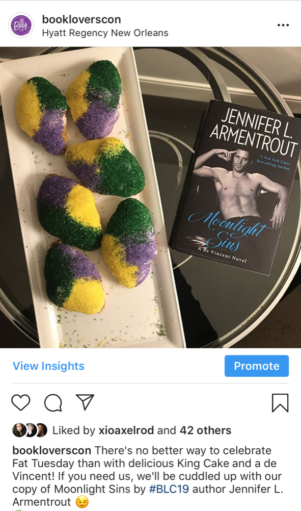 A screenshot of a Book Lovers Con Instagram post shows a print copy of Jennifer L. Armentrout's Moonlight Sins sitting next to a plate of mini King Cakes.